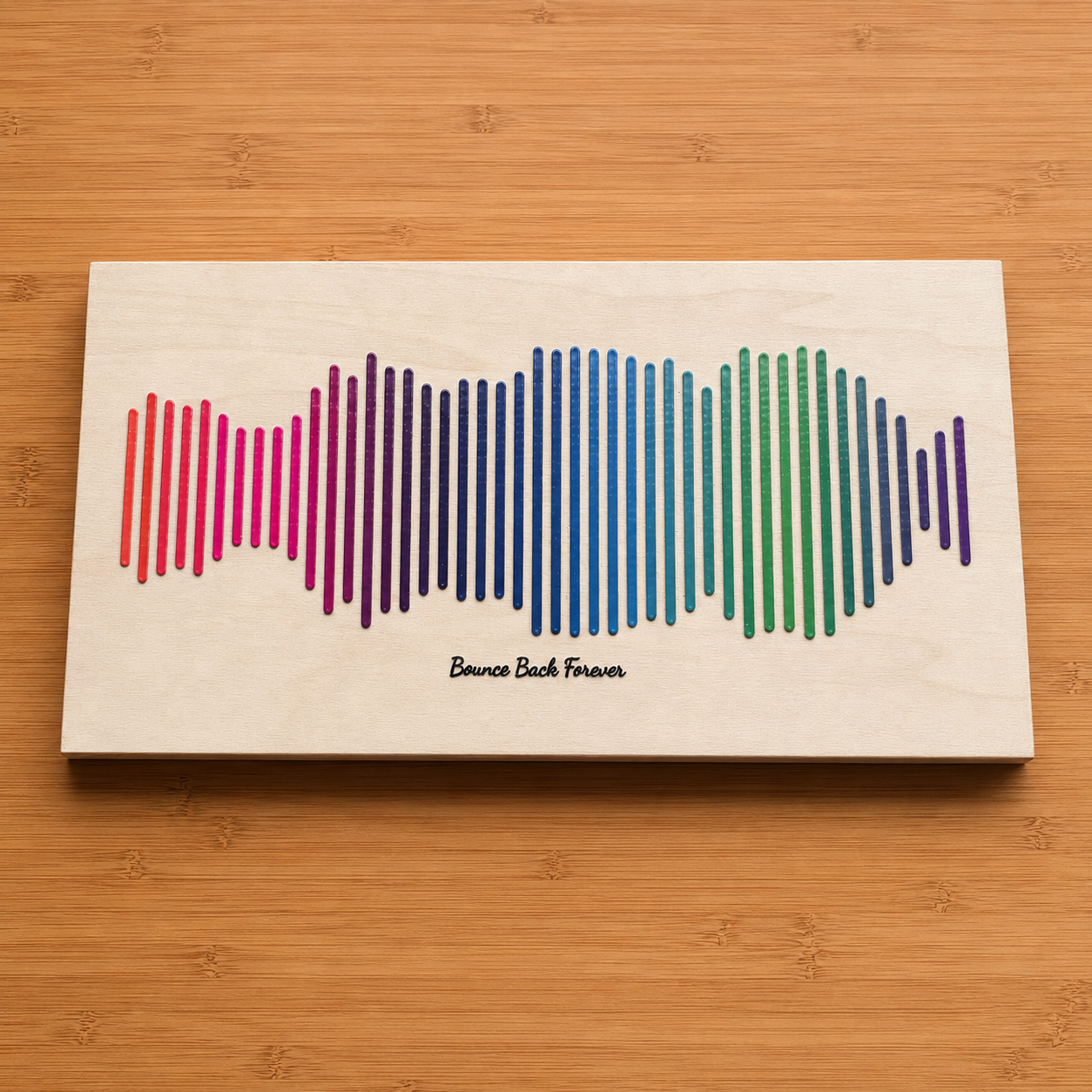 A white wood wall panel with a raised rainbow waveform from the song Bounce Back and the words Bounce Back.